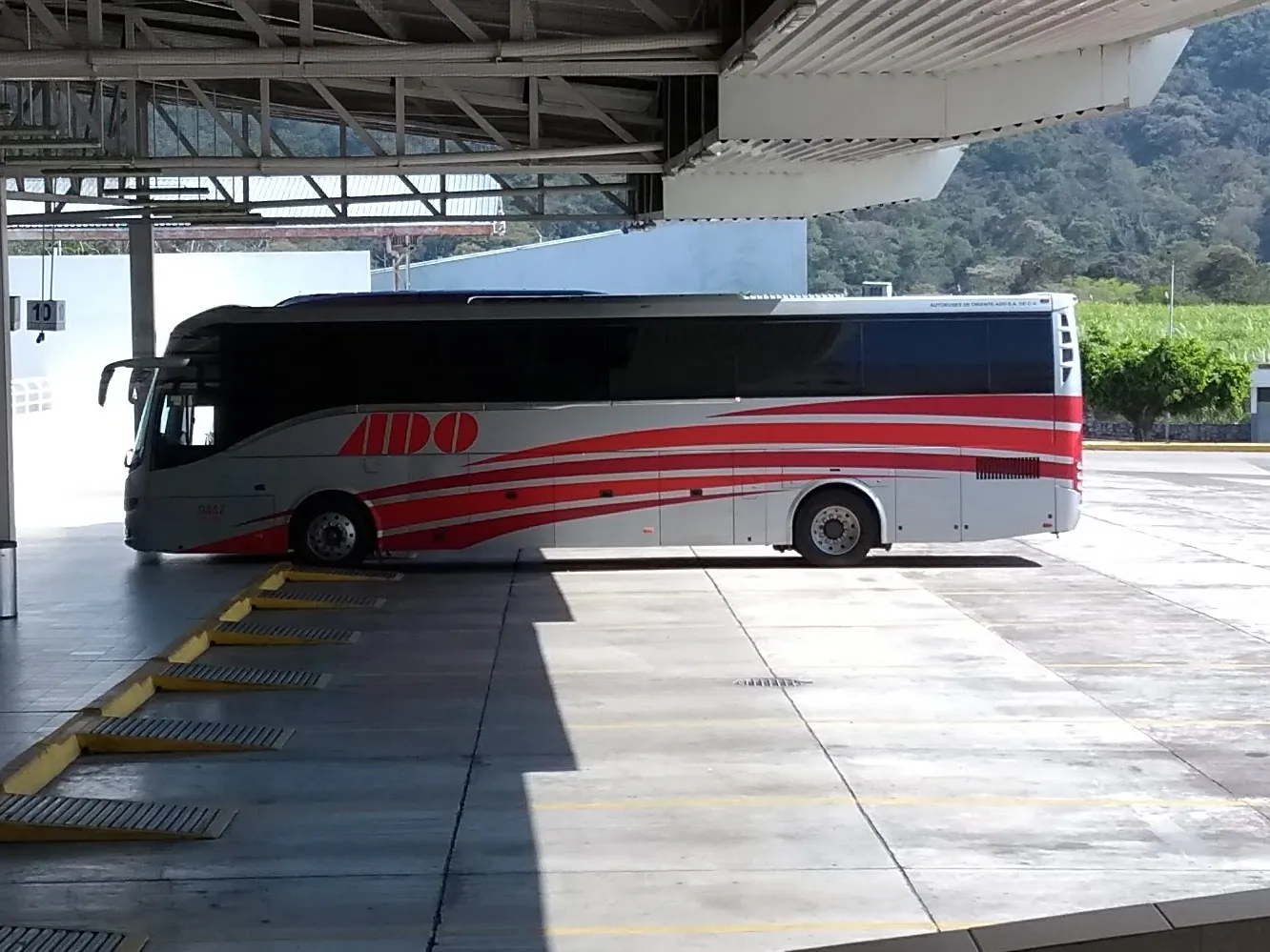 Autobús de ADO, gris con franjas rojas, estacionado en los andenes techados de la central de autobuses de Córdoba, Veracruz.