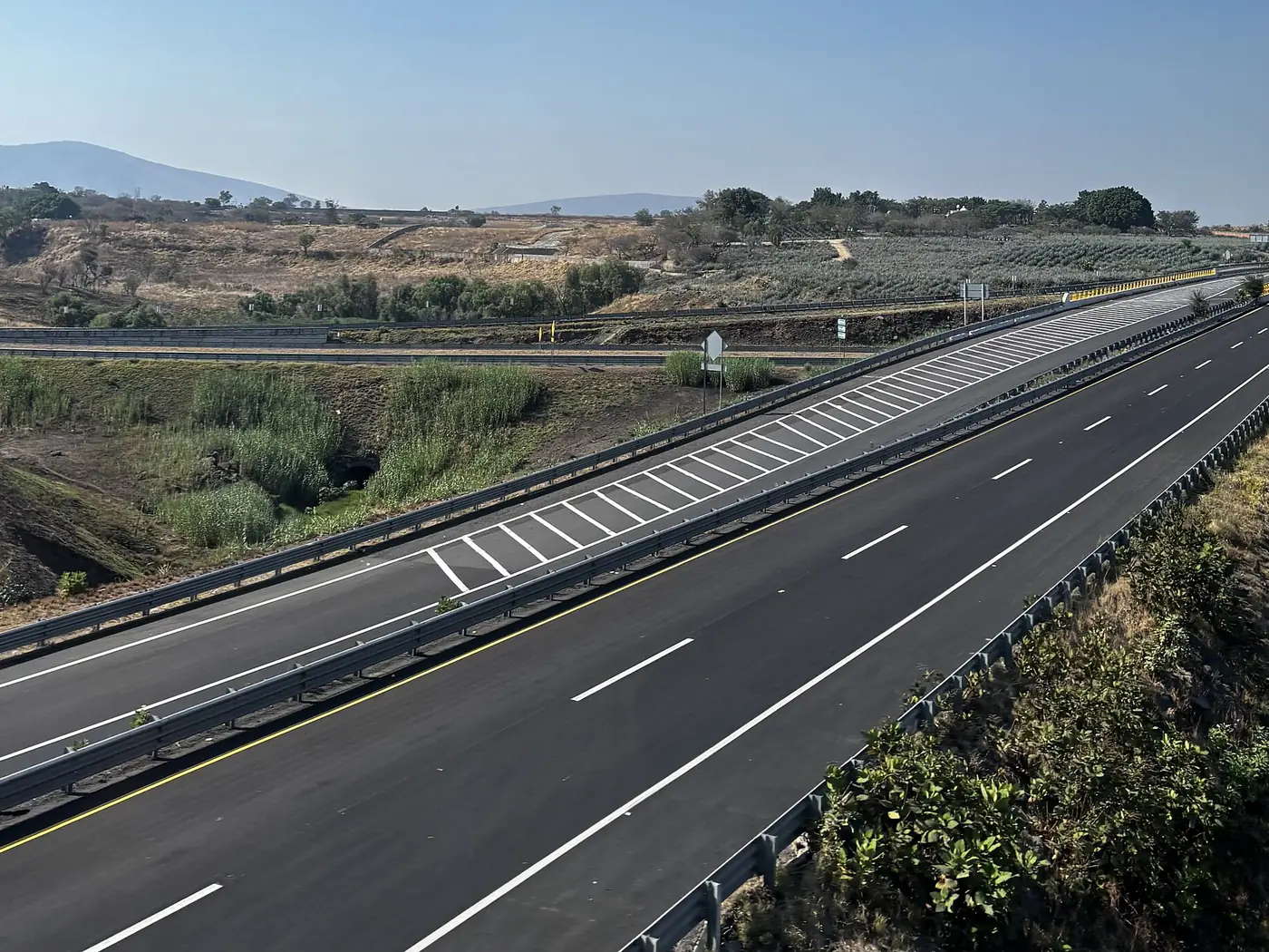 El Libramiento Guadalajara (GUA 10D) donde empieza, en el entronque con las autopistas 80D y 90D en Jalisco, con cuatro carriles vacíos entre campos de agave.