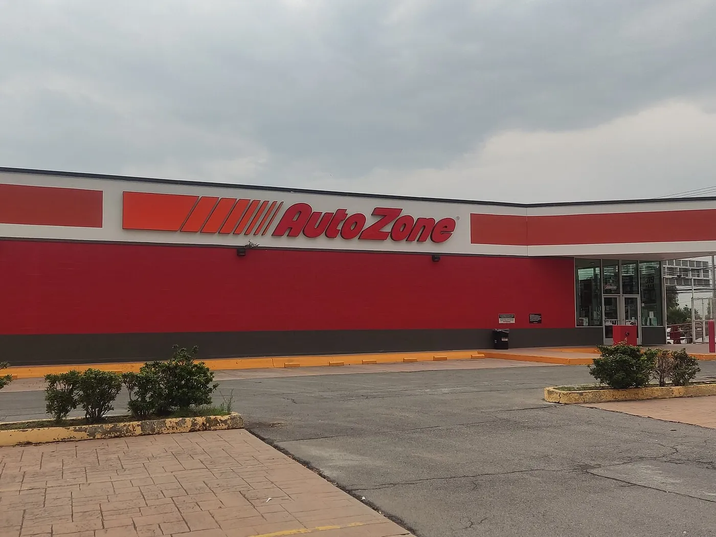 Tienda AutoZone del Coacalco Power Center, Estado de México, con su fachada roja, el letrero sobre el muro y la entrada de cristal a la derecha.