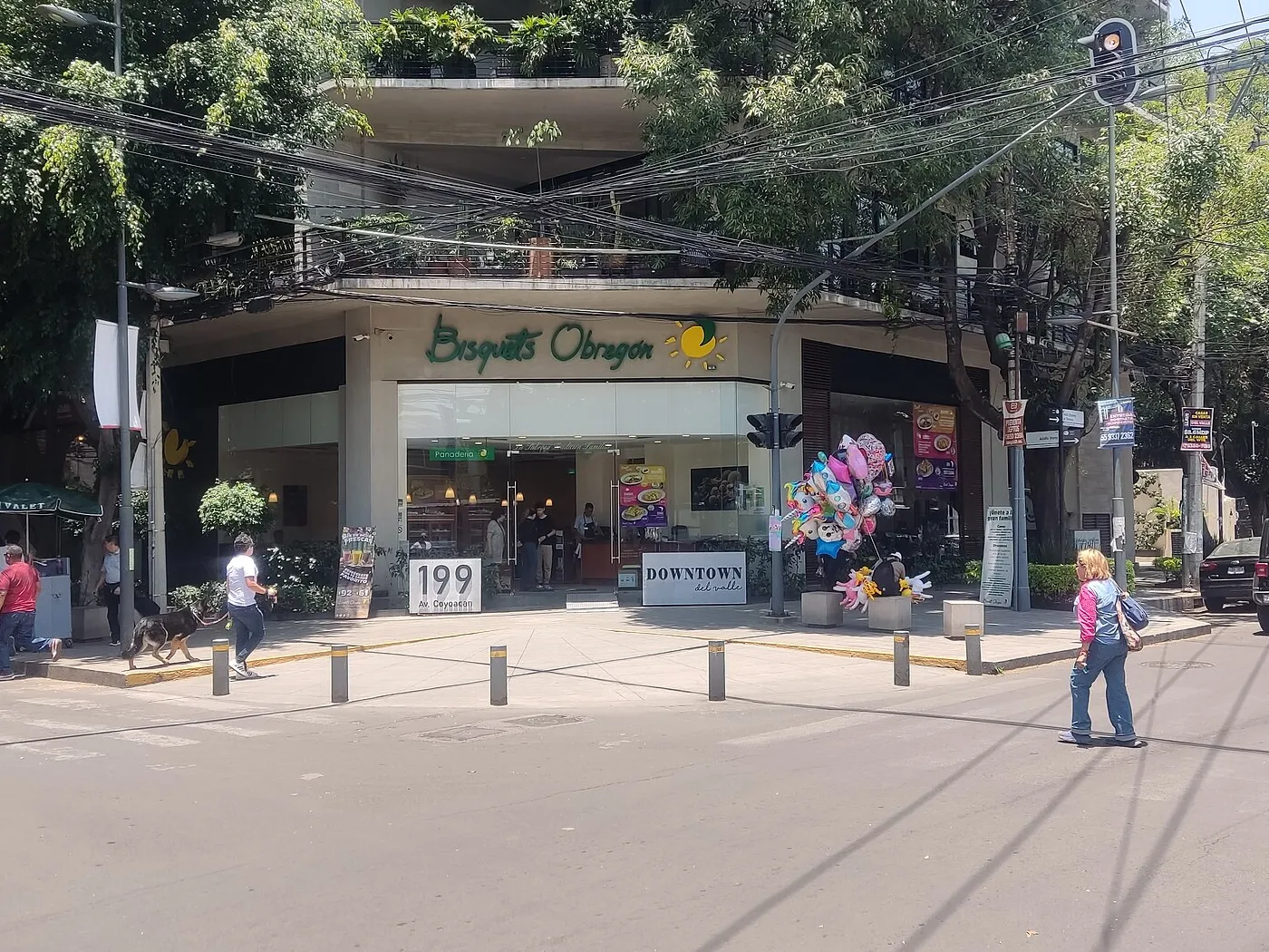 Restaurante Bisquets Obregón en la esquina de Av. Coyoacán 199, colonia Del Valle, Ciudad de México, con el letrero verde y el sol amarillo sobre la entrada de vidrio y la panadería al fondo.