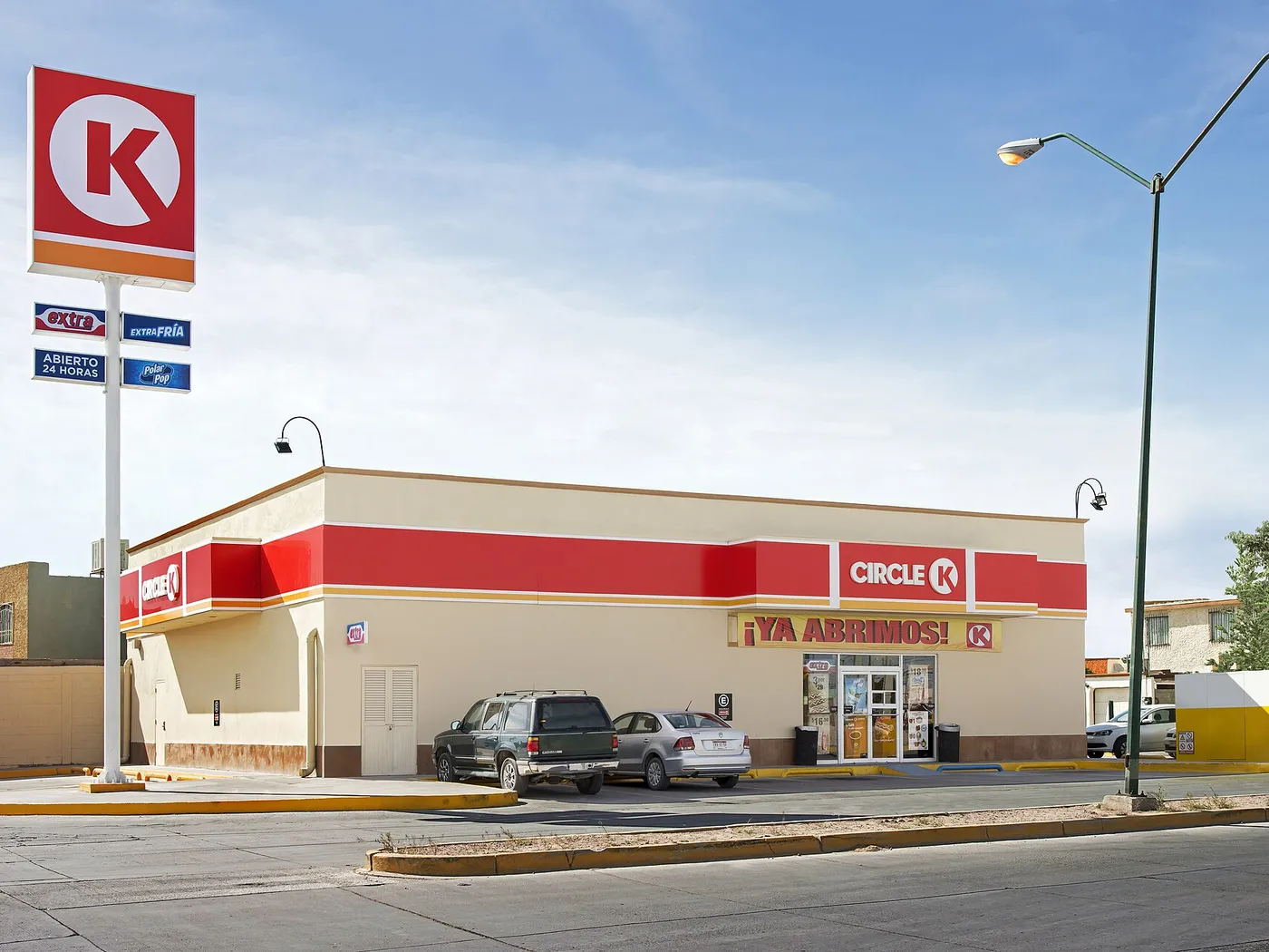 Tienda Circle K en Ciudad Juárez, Chihuahua, con el poste del logo rojo y los letreros de Extra y «Abierto 24 horas», y la manta «¡Ya abrimos!» sobre la entrada.