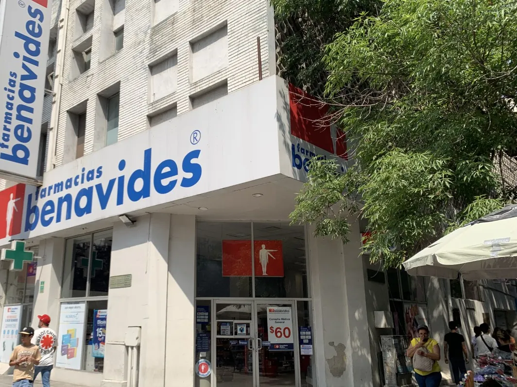 Sucursal de Farmacias Benavides en la calle peatonal Morelos de Monterrey, Nuevo León, con su letrero azul y blanco en la esquina y la figura roja sobre la entrada.