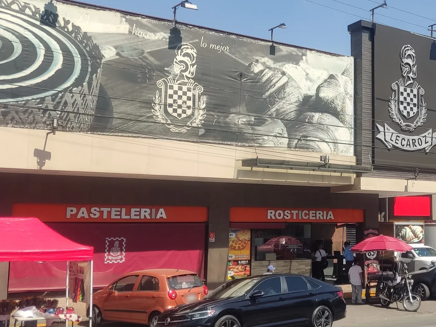 Panadería Lecaroz en Nueva Atzacoalco, Ciudad de México, con los letreros Pastelería y Rosticería bajo un anuncio con el escudo y el nombre Lecaroz.
