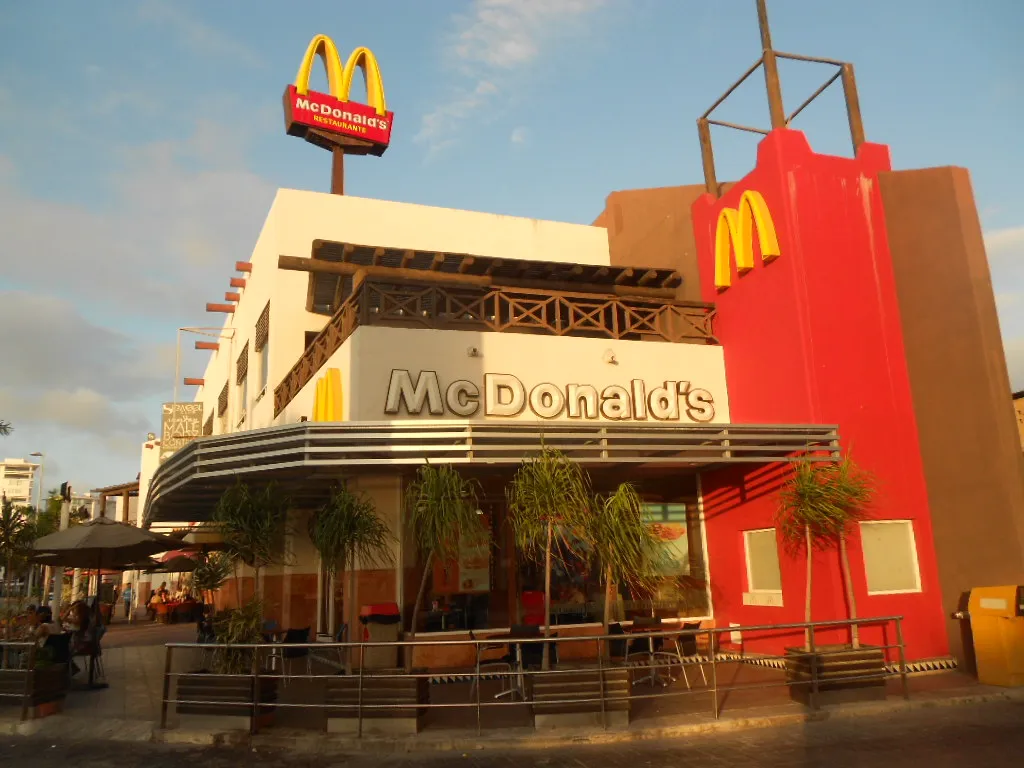Restaurante McDonald's del Boulevard Kukulcán, en Cancún, Quintana Roo, con los arcos amarillos sobre un muro rojo y su terraza al frente.