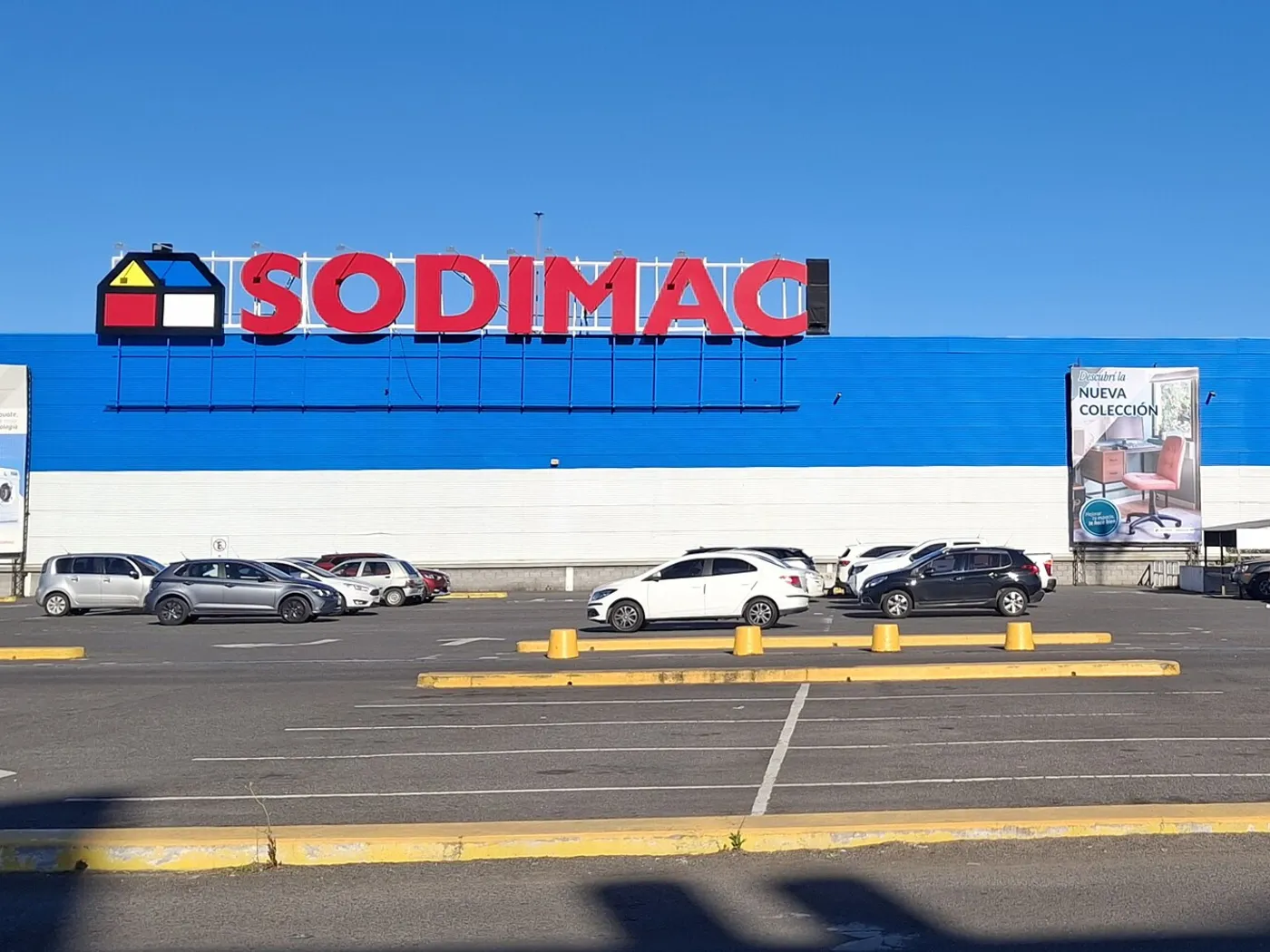 Fachada de una tienda Sodimac en Villa Chacabuco, provincia de Buenos Aires, Argentina, con el letrero rojo sobre la pared azul y autos en el estacionamiento.