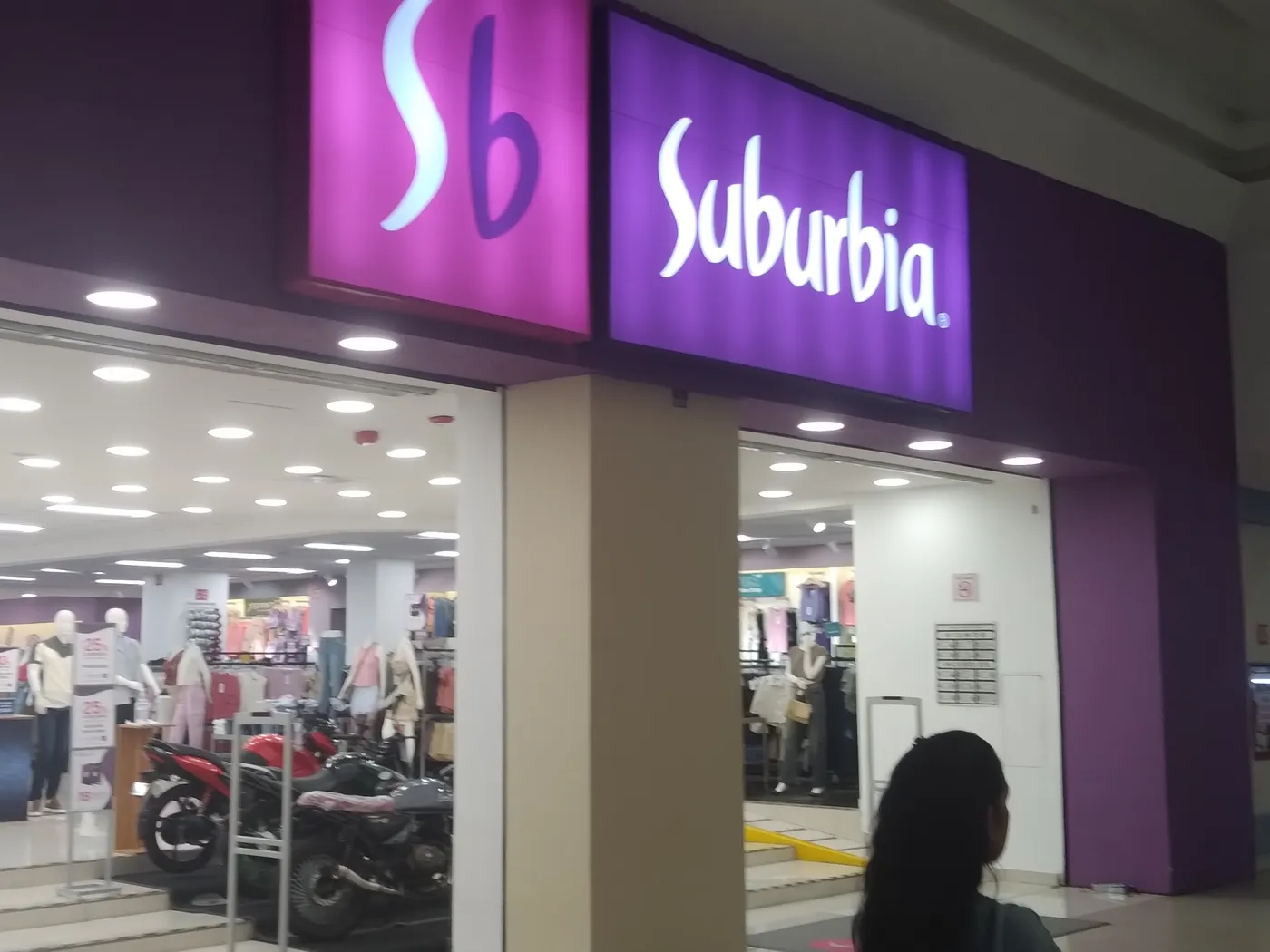 Entrada de la tienda Suburbia de Gran Plaza Mazatlán, Sinaloa, con sus letreros morados «Sb» y «Suburbia» y motocicletas en exhibición junto a la puerta.